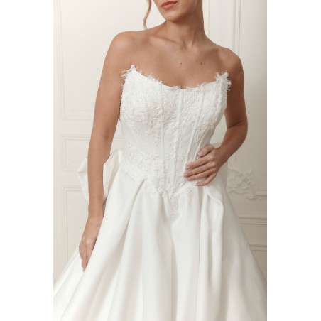 Robe de mariée bustier couture PRÉCIEUSE avec jupe volumineuse fluide et grand nœud dans le dos, disponible chez Promarried.